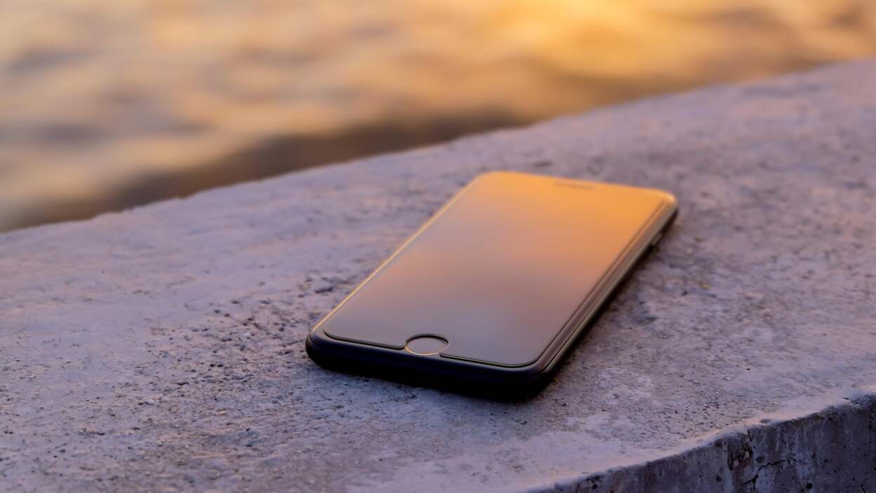 iPhone resting on a wall, presumably left behind accidentally by its owner.