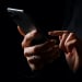 Hands holding smartphone on dark background