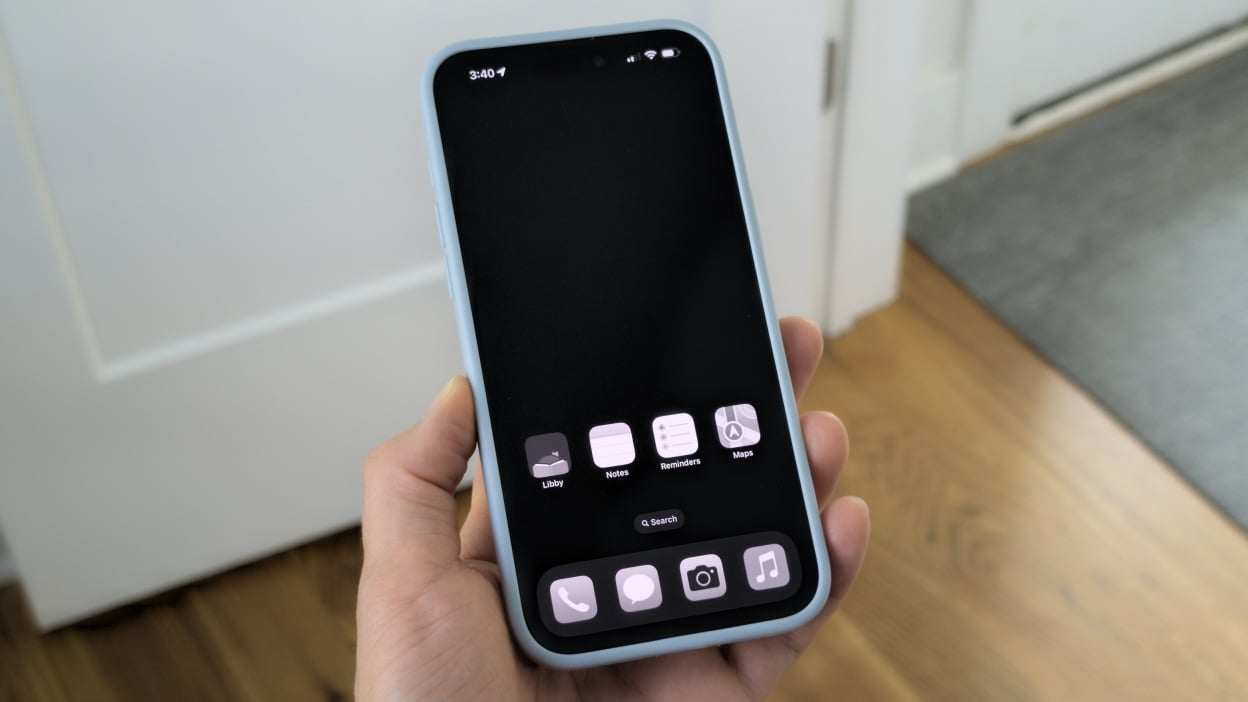 A hand holding an iPhone with a phone in in greyscale and only 4 apps