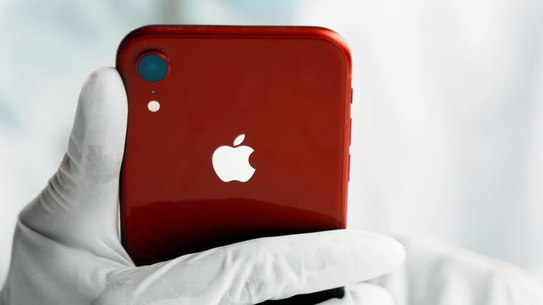 A person holding an iPhone XR while wearing gloves