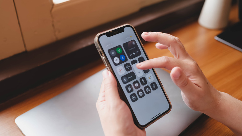A person accessing the iPhone's Control Center, which shows the Portrait Orientation Lock is enabled.